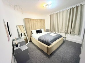 A hotel room with a bed, a bedside table, a mirror, and a window with curtains. - 7 Guests 3-Br free parking-near Manchester Airport (Cheadle)