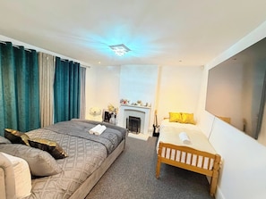A bedroom with a large bed, a smaller bed, a fireplace, and a TV. - 7 Guests 3-Br free parking-near Manchester Airport (Cheadle)