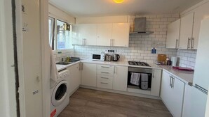 Une cuisine compacte équipée d’un lave-linge, d’un four à micro-ondes et d’une cuisinière.