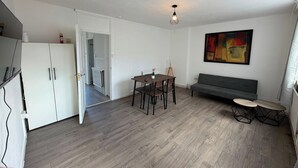 Une pièce comprenant une table à manger, des chaises, un canapé, une petite table et un radiateur.