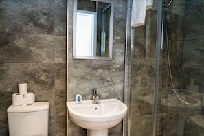 Ein Badezimmer mit einem weißen Waschbecken, einem Spiegel und einer Dusche mit Glastüren.