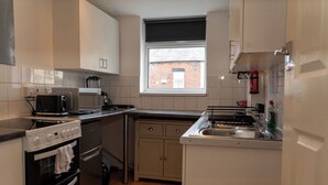 Pieni, käytännöllinen keittiö, jossa on liesi, mikroaaltouuni ja pesuallas.