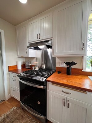 A kitchen with white cabinets, a stainless steel range hood, a gas stove, and a built-in oven. - Tranquil 4-bedroom Mountain Top Cottage In Charming Twain Harte (Twain Harte)
