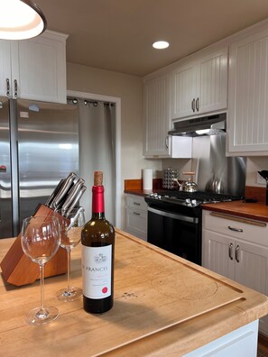 A kitchen with a wooden countertop, a stainless steel refrigerator, a wine bottle, and two wine glasses. - Tranquil 4-bedroom Mountain Top Cottage In Charming Twain Harte (Twain Harte)