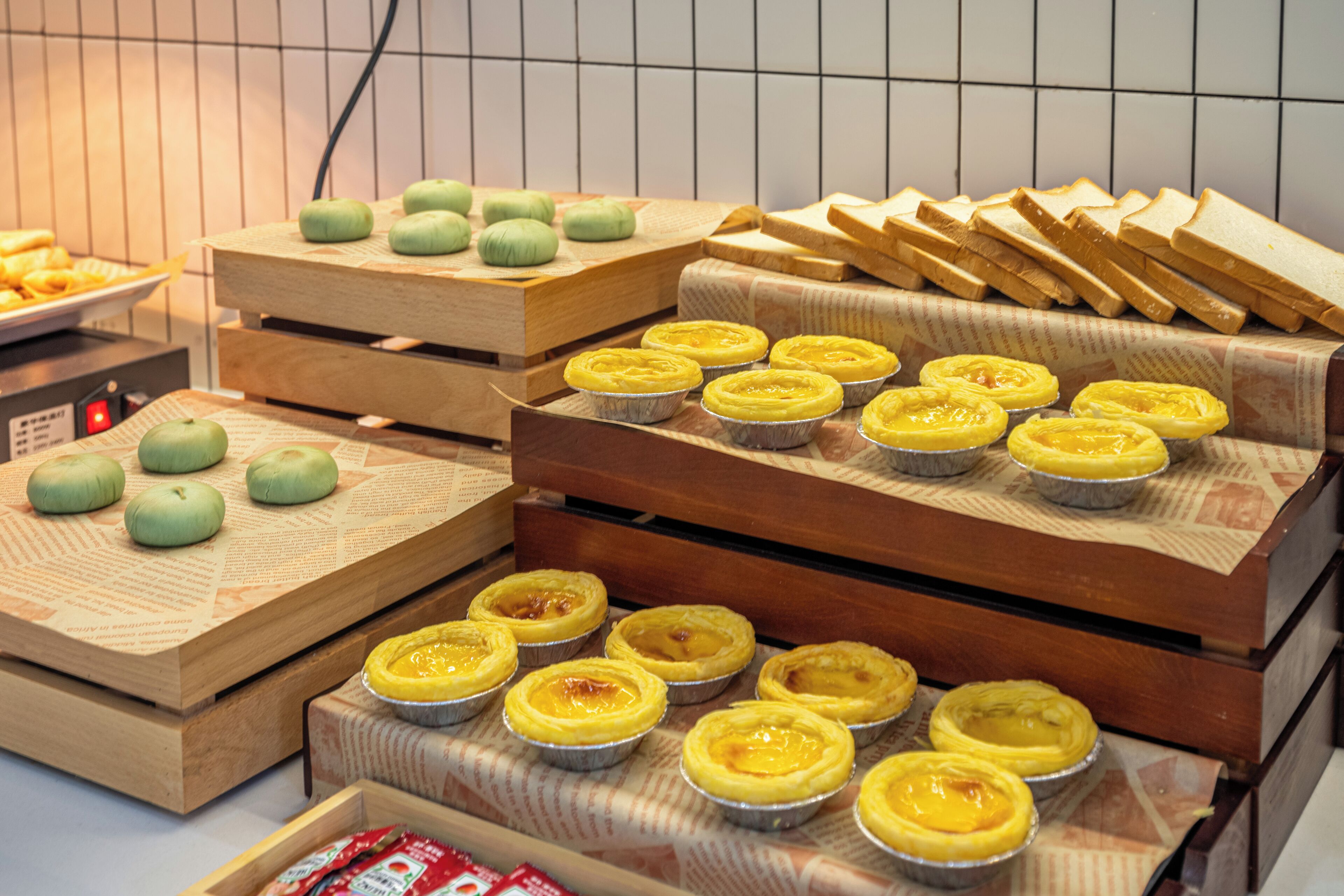 Diversos doces e pastelaria expostos em suportes de madeira.