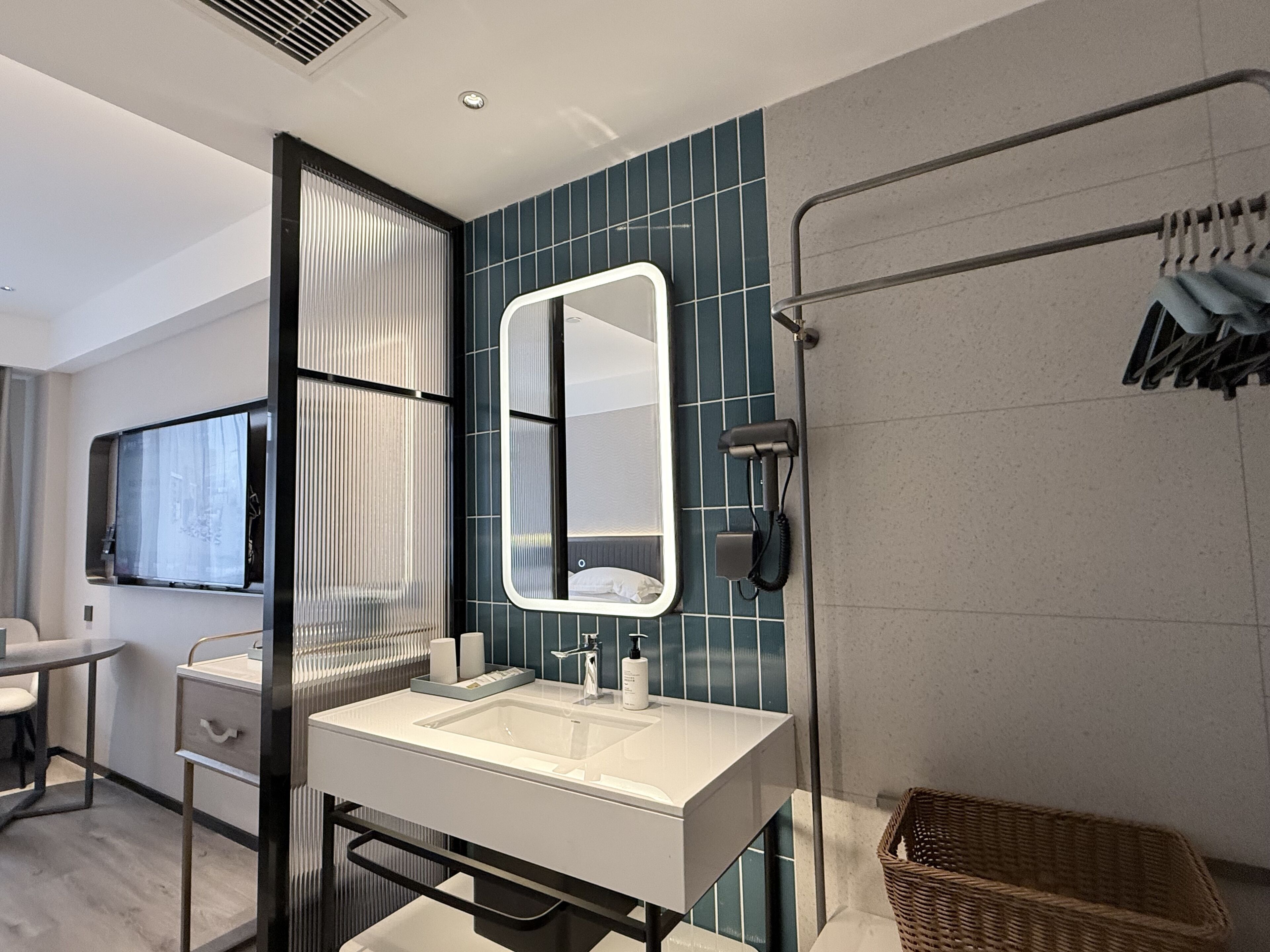 A modern bathroom with a large mirror, a sink, and a shower area.