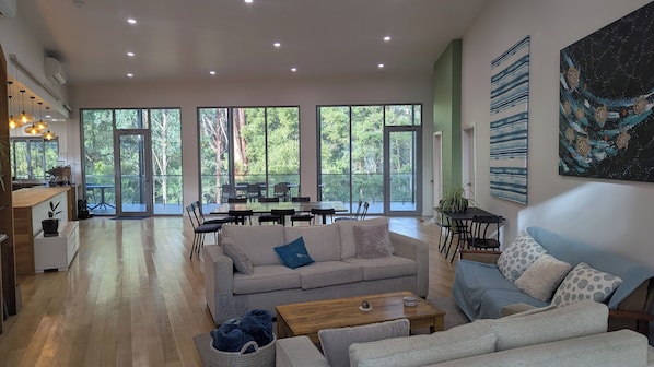A spacious living area with a large window, a sofa, a coffee table, and a dining area with chairs and a table.