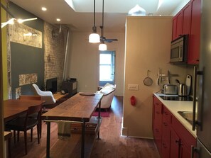 A modern kitchen with red cabinets, a microwave, and a sink. - The Bohemian - 2 bedrooms and so much more... (Stratford)