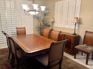 A dining area with a wooden table, chairs, a chandelier, and a cabinet.