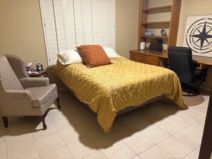 A bedroom with a bed, a chair, a desk, and a compass wall decoration.