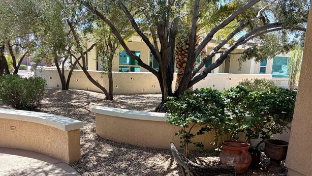 Una zona patio esterna con una sedia in vimini, un tavolino e piante in vaso.