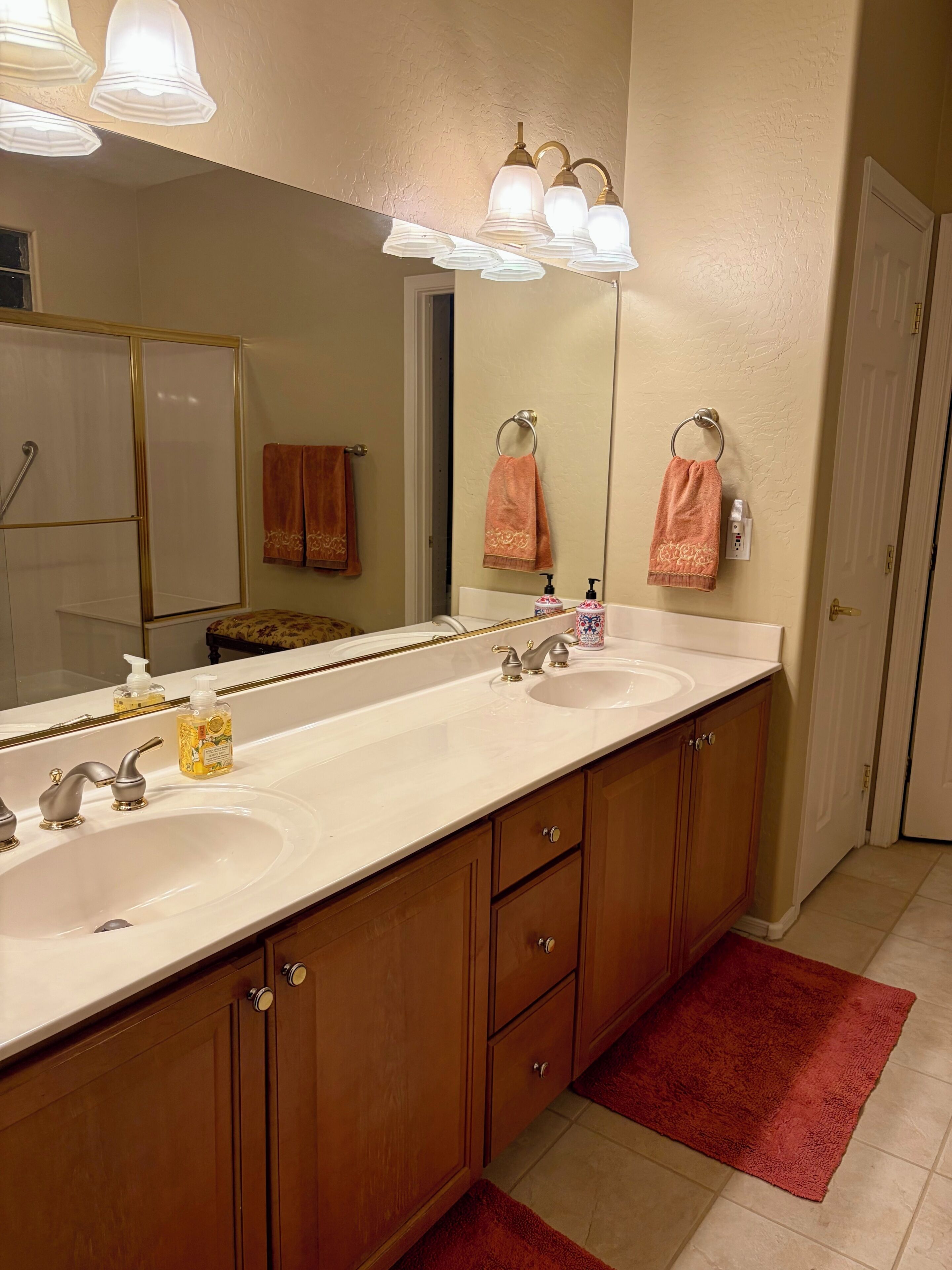 A bathroom with a double sink, vanity, and a large mirror.