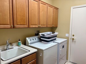 A kitchen with wooden cabinets, a sink, a stove, and a washing machine.