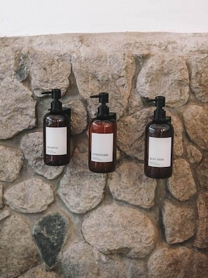Three bottles of liquid products against a stone wall. - Seashell suite beachfront with pool access (Saint Andrew Parish)