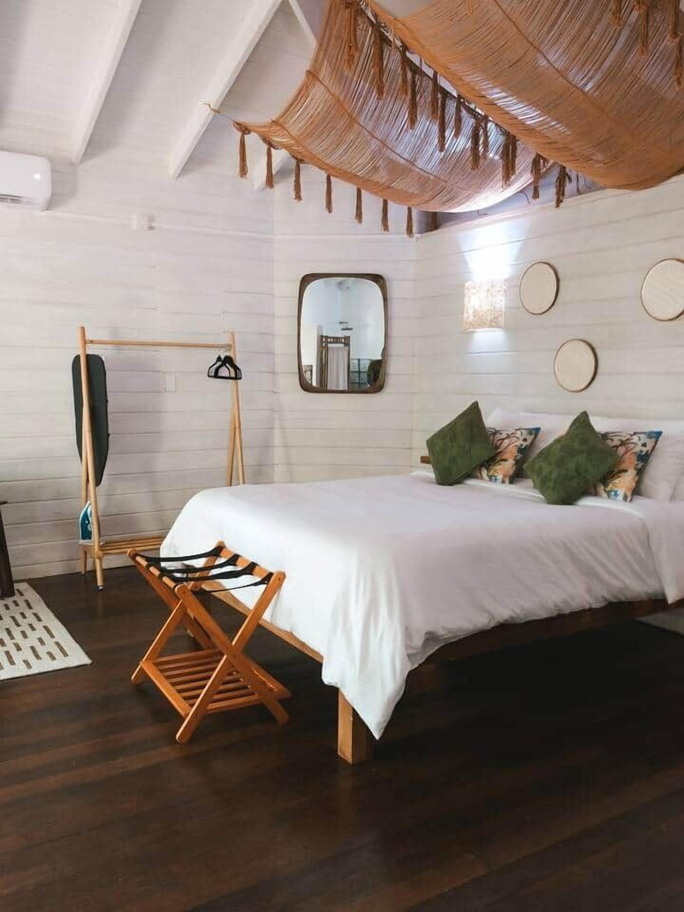 Une chambre à coucher avec un lit, un fauteuil suspendu, un miroir et une étagère fixée au mur.