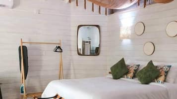Une chambre à coucher avec un lit, un fauteuil suspendu, un miroir et une étagère fixée au mur.