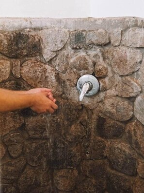 A hand turning a stone wall-mounted faucet.