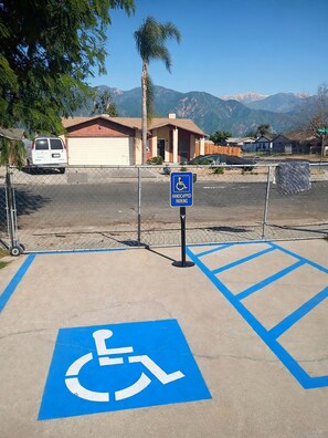 Une zone de stationnement avec un panneau indiquant les places réservées aux personnes handicapées et des marquages bleus au sol pour faciliter l’accès.