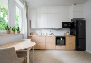 Eine moderne Küche mit weißen Schränken, einem schwarzen Kühlschrank und einem Essbereich mit Tisch und Stühlen.