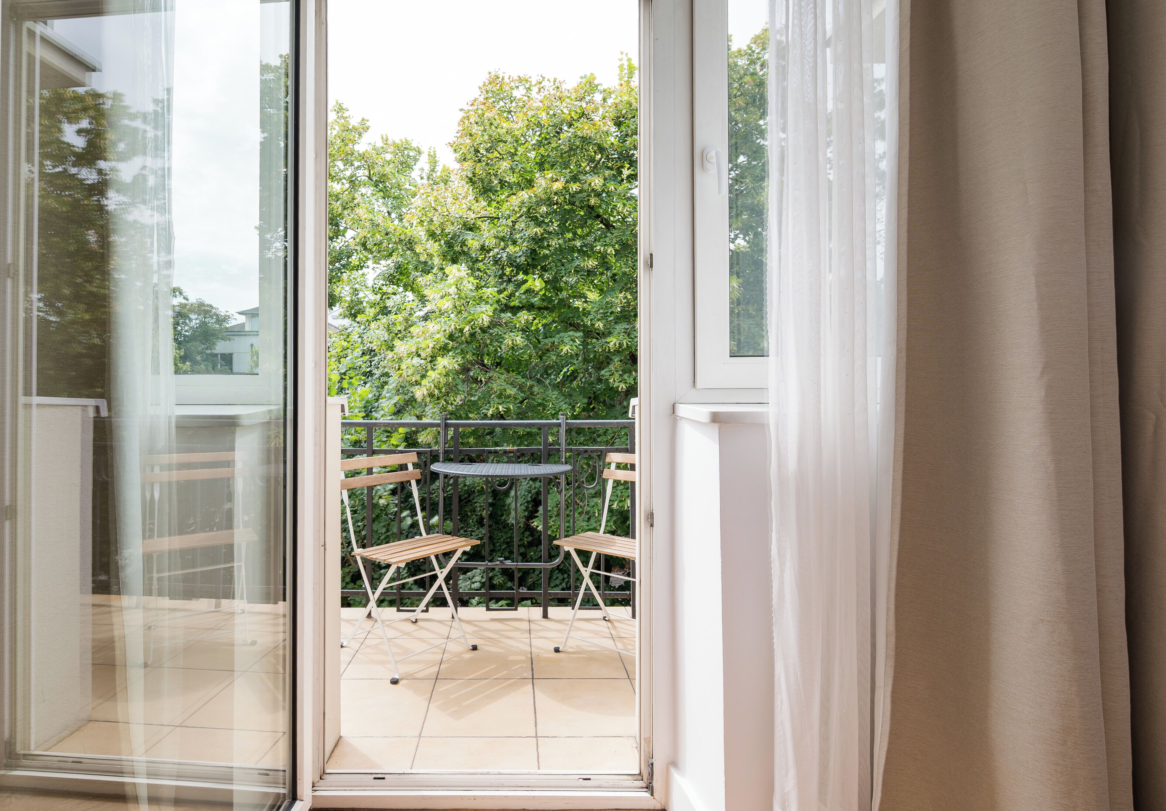 A view through a glass door to an outdoor patio with a table and chairs.