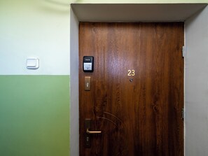 A wooden door with a numeric keypad and a lock, and a small light switch on the wall. - Atlas Arena Brick Loft Apartment (Łódź)