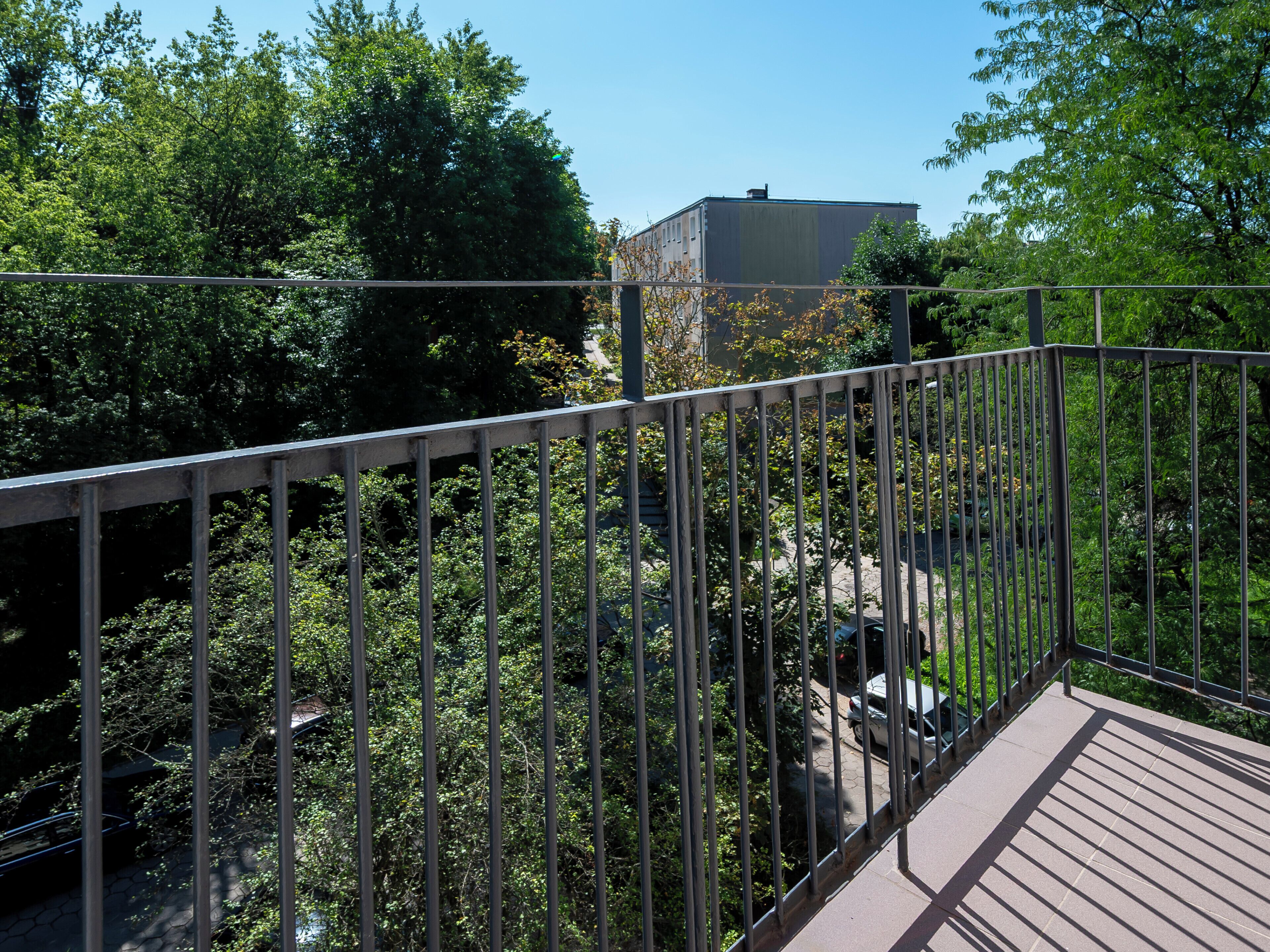 Ein Metallbalkon mit Blick auf Bäume und ein Gebäude im Hintergrund.