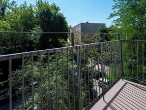 A metal balcony with a view of trees and a building in the background. - Atlas Arena Brick Loft Apartment (Łódź)