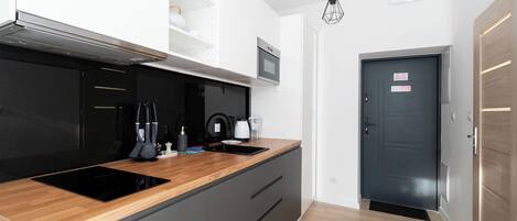Une cuisine moderne avec un poêle noir, un plan de travail en bois et des armoires grises.
