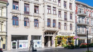 En historisk byggnad med utsmyckade arkitektoniska detaljer, en butiksfasad med en blomsterdekoration och en gatlykta.