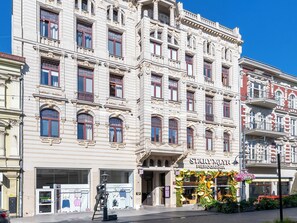 A historic building with ornate architectural details, a storefront with a floral display, and a street lamp. - Piotrkowska Elegant Studio (Łódź)