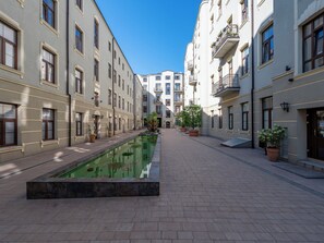 A courtyard with a rectangular pool, potted plants, and multi-story buildings with balconies. - Piotrkowska Elegant Studio (Łódź)