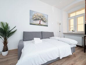 Ein Schlafzimmer mit einem Bett, einer Topfpflanze, einem Gemälde und einem Fenster.