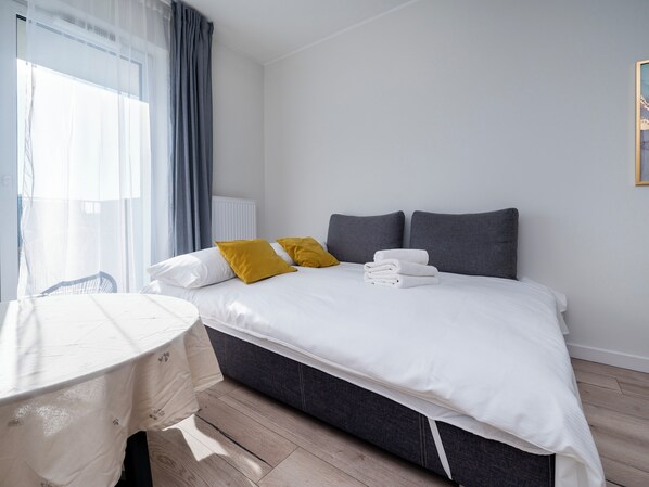 Una habitación de hotel con una cama, una mesita de noche y un ventanal con cortinas.