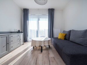 Una sala de estar moderna con un sofá gris, una mesa redonda y un armario gris.