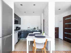 A modern kitchen with a dining area, featuring a refrigerator, stove, and cabinets. - 1 Maja Homely Apartament (Łódź)