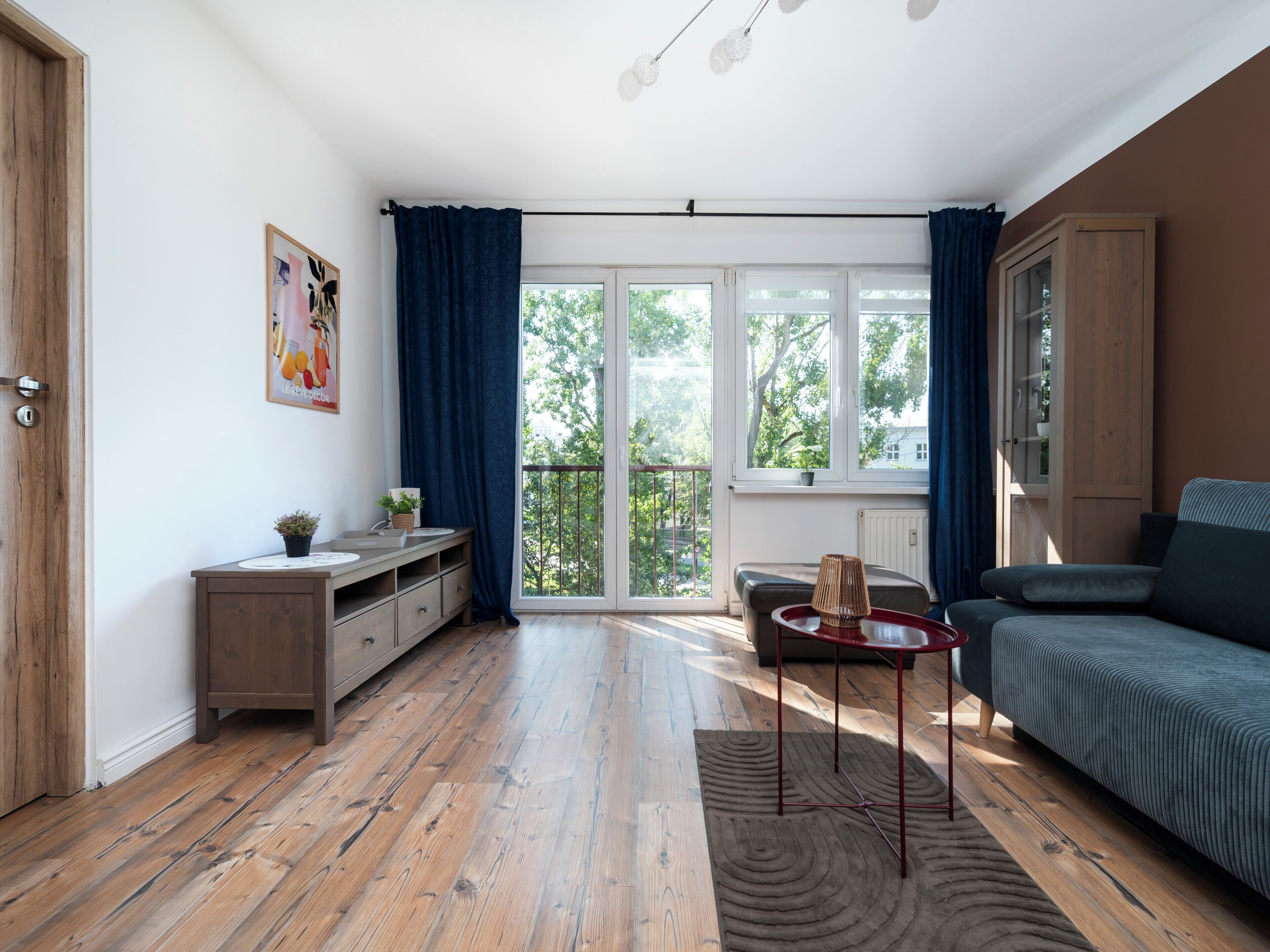 Una sala de estar moderna con un sofá, una mesita, un armario y vistas al exterior a través de amplios ventanales.