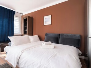 A hotel room with a bed, a wardrobe, a window with curtains, and a framed picture on the wall. - 1 Maja Homely Apartament (Łódź)