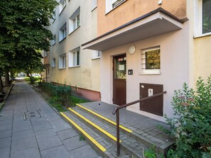 A residential building with a visible entrance, a door marked with the number 16-30, and a staircase with yellow safety lines. - 1 Maja Homely Apartament (Łódź)