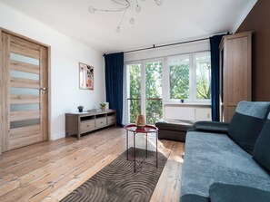 Una sala de estar moderna con un sofá, una mesita, un mueble aparador y un ventanal con cortinas.