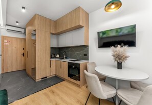 A modern kitchen with wooden cabinets, a black countertop, and a built-in oven. - Global Park Superior Studio (Katowice)