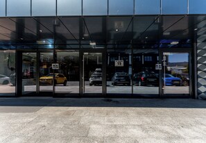A building entrance with glass doors, a street view, and a clear sky. - Global Park Superior Studio (Katowice)