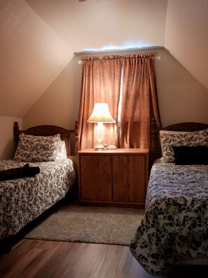 A bedroom with two beds, a nightstand with a lamp, and a window with curtains. - Three Bedroom Cabin Escape near Dolores River on Private 300 Acre Ranch! (Dolores)