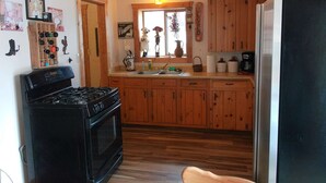 A kitchen with wooden cabinets, a black stove, and a refrigerator. - Three Bedroom Cabin Escape near Dolores River on Private 300 Acre Ranch! (Dolores)