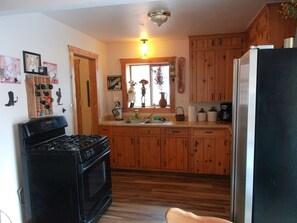 A kitchen with wooden cabinets, a black stove, and a refrigerator. - Three Bedroom Cabin Escape near Dolores River on Private 300 Acre Ranch! (Dolores)