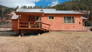A wooden cabin with a porch, windows, and a metal roof, set against a mountainous backdrop. - Three Bedroom Cabin Escape near Dolores River on Private 300 Acre Ranch! (Dolores)
