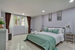 Ein Schlafzimmer mit einem Bett, Nachttischen, einer Lampe und zwei gerahmten Bildern an der Wand.