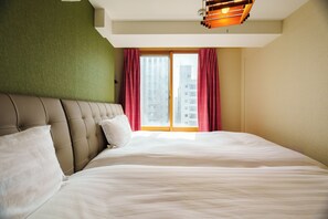 Ein Hotelzimmer mit einem großen Bett, einer Kopfteil, einem Fenster mit Vorhängen und einer Deckenleuchte.