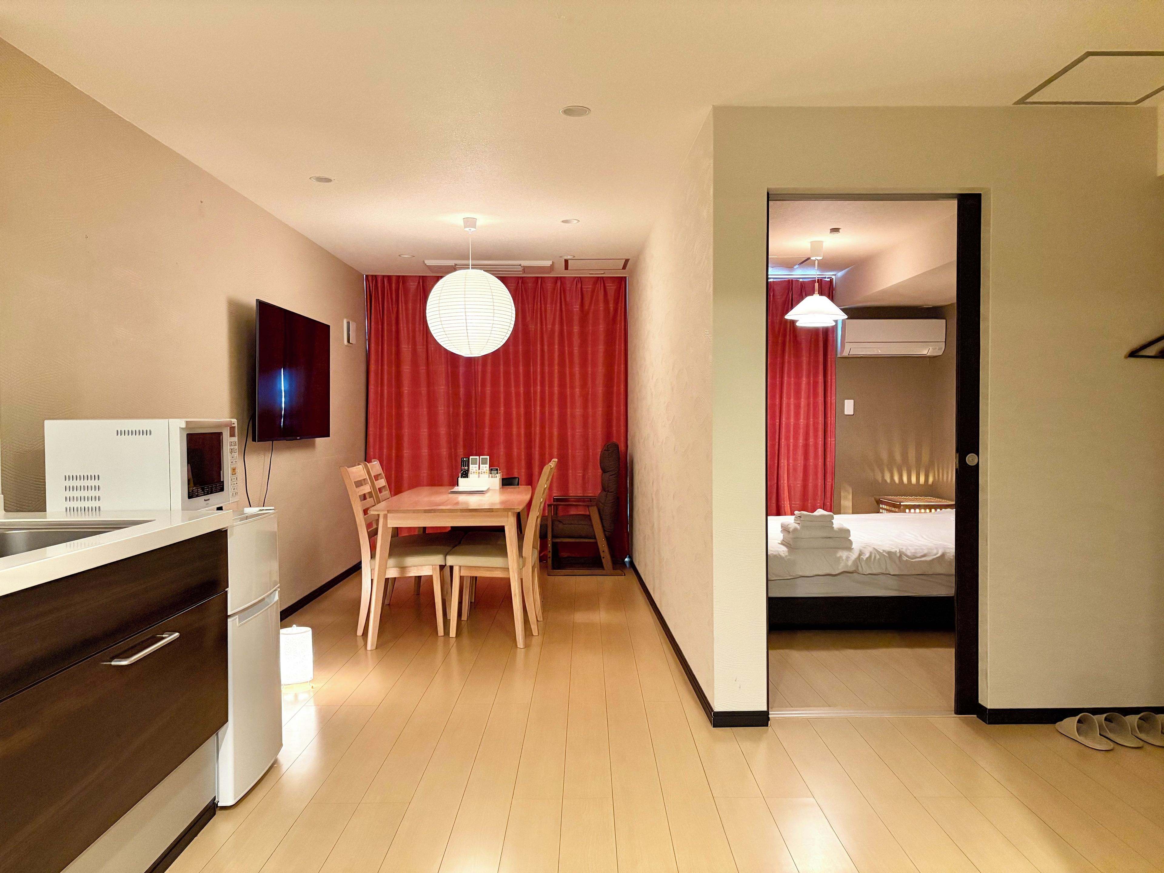 Habitació d'hotel petita amb cuina americana, zona de dinar i un dormitori separat.