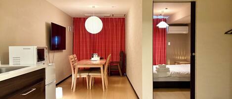 A compact hotel room with a kitchenette, a dining area, and a separate bedroom.