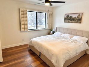 A bedroom with a bed, a window with shutters, a ceiling fan, and a painting on the wall. - 4min walk to Downtown Flagstaff 2bd/1.5ba NEW! (Flagstaff)
